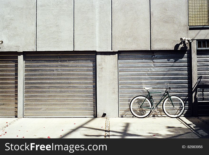 Bicycle leaning against garage door on sunny day. Bicycle leaning against garage door on sunny day.
