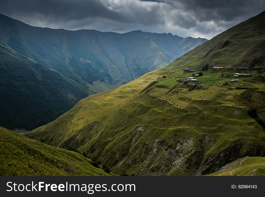 Village on hillside of green mountain with cloudy skies. Village on hillside of green mountain with cloudy skies.