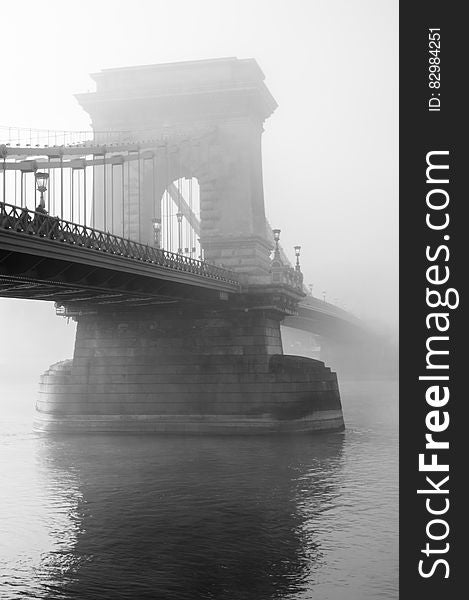 Fog over stone stanchion of suspension bridge in black and white. Fog over stone stanchion of suspension bridge in black and white.