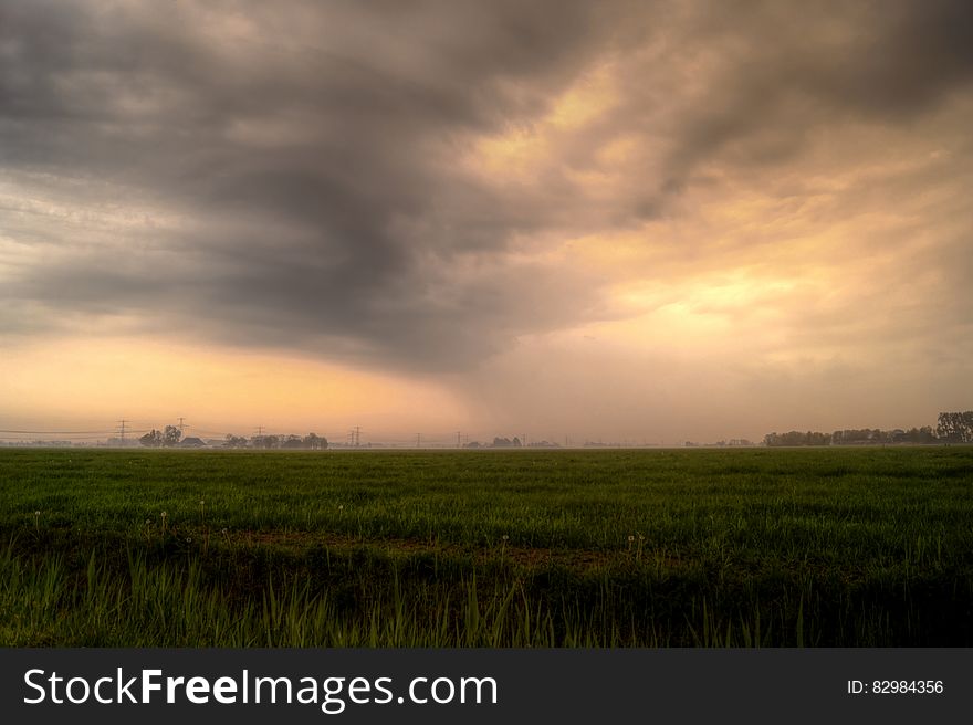 Sunset in stormy skies over rural meadow.