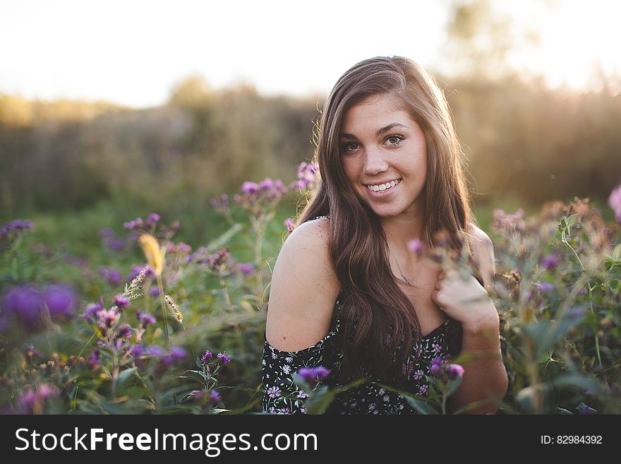 Woman in Black Off Shoulder Dress Standing in Green Flower Field during Daytime