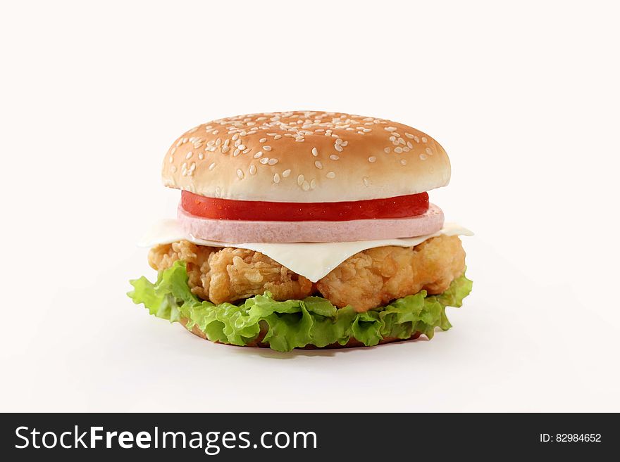 Giant hamburger in seeded bun with cheese, ham, tomato and crispy green lettuce, white background. Giant hamburger in seeded bun with cheese, ham, tomato and crispy green lettuce, white background.