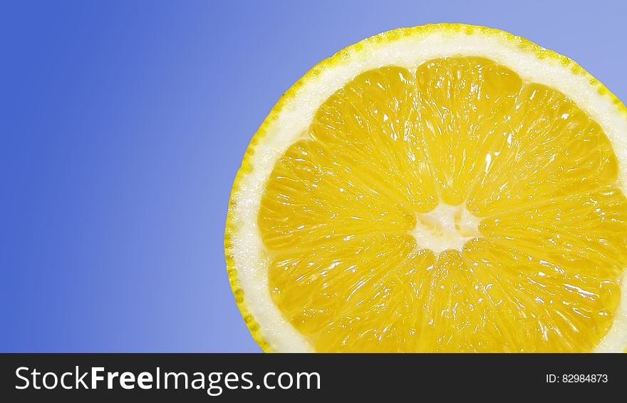 Closeup of a bright yellow half lemon against a sky blue background. Closeup of a bright yellow half lemon against a sky blue background.