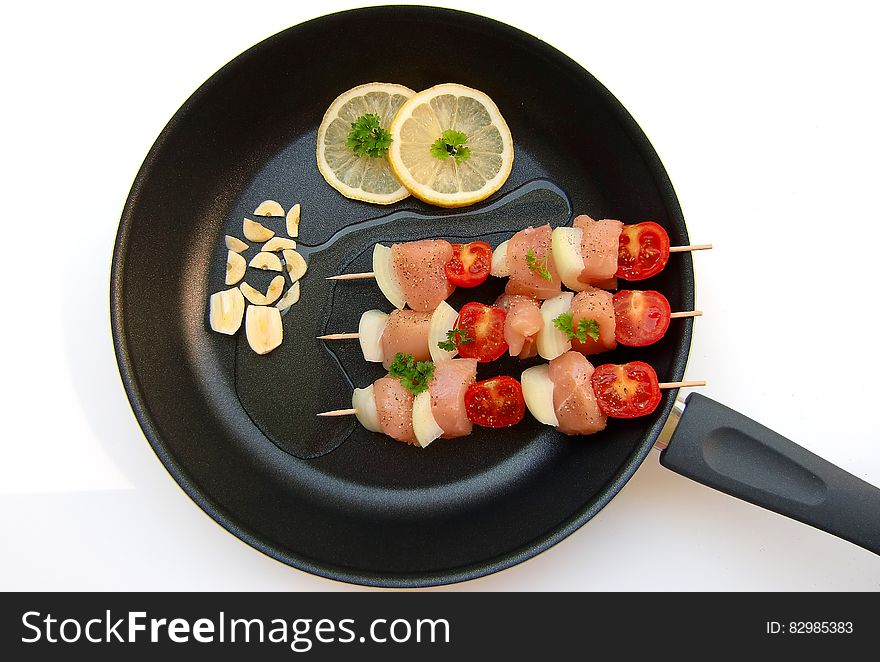 Barbecue Stick Beside Lemon On Black Frying Fan