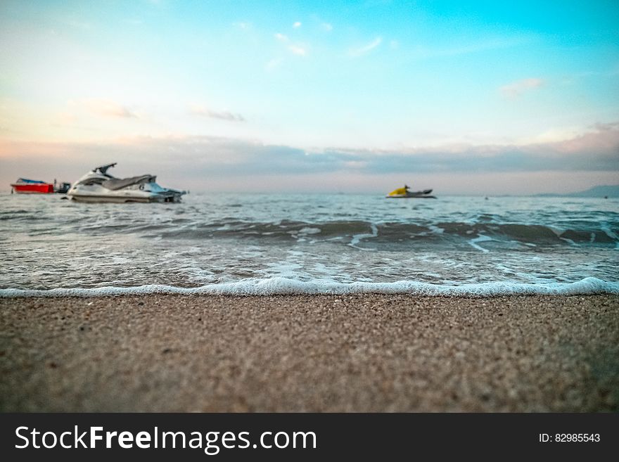 Jet skis in waves offshore of sandy beach on sunny day. Jet skis in waves offshore of sandy beach on sunny day.