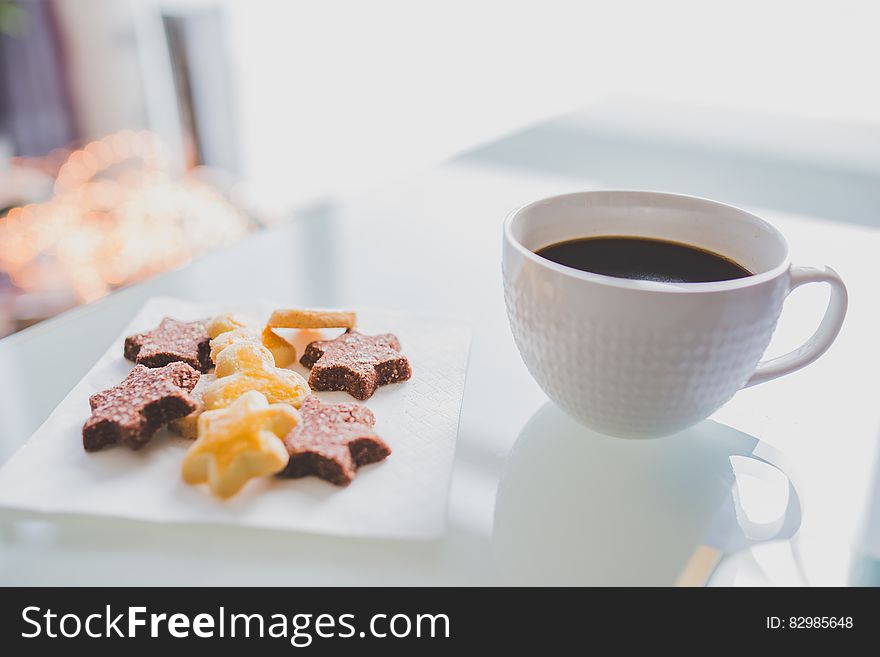 White Tea Cup Beside White Square Saucer With Star Shaped Cookies