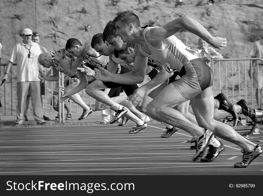 Athletes Running on Track and Field Oval in Grayscale Photography