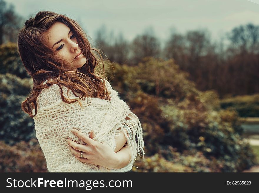 Portrait of woman wrapped in white shawl standing outdoors with serious expression. Portrait of woman wrapped in white shawl standing outdoors with serious expression.