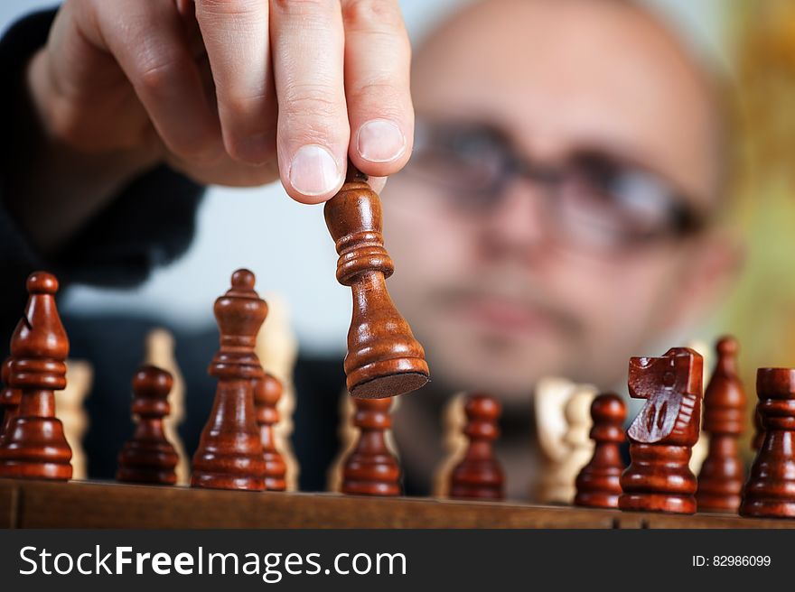 Close up of man's hand moving wooden chess pieces on board. Close up of man's hand moving wooden chess pieces on board.