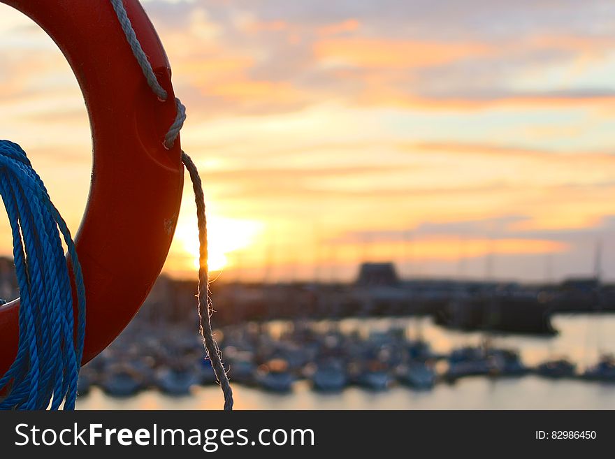 Close up of life ring next to boats in harbor at sunset. Close up of life ring next to boats in harbor at sunset.