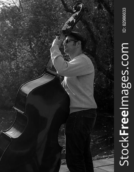 Musician playing bass outdoors in black and white.