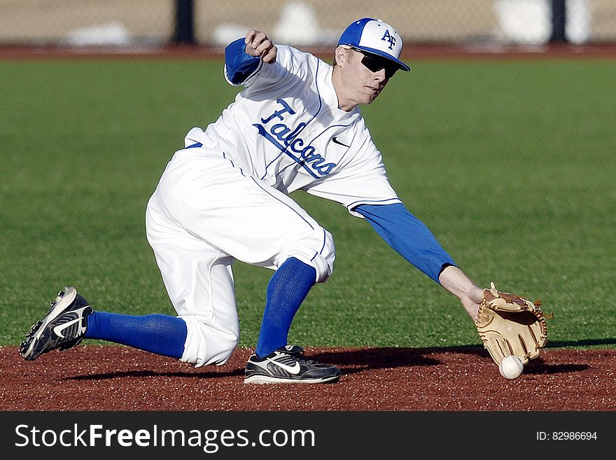 Man Wearing Blue and White Falcons Baseball Jersey Shirt With Brown Baseball Gloves Catching White Baseball