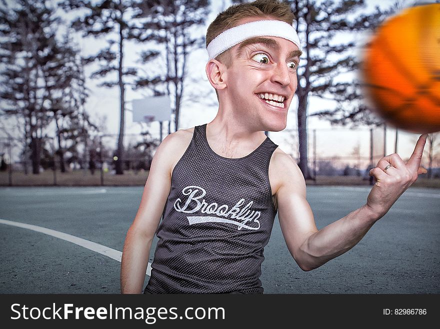 Person in Grey Tank Top Spinning Ball on Forefinger