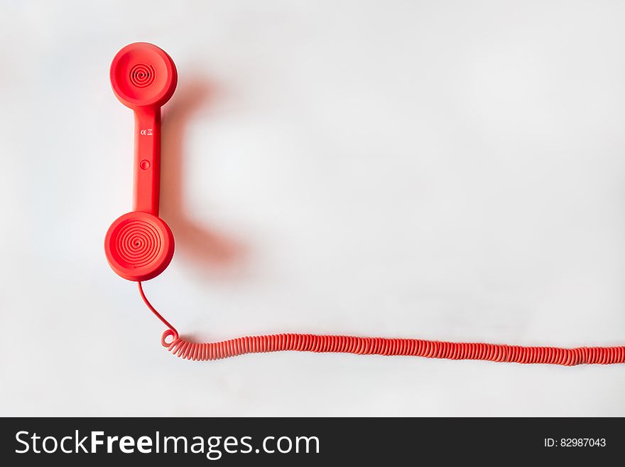 Red telephone receiver and cable on white background with copy space.