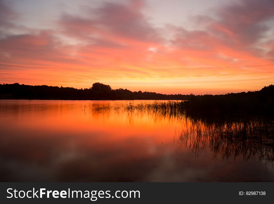 Sun setting over reeds along banks of lake. Sun setting over reeds along banks of lake.