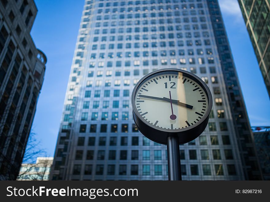 Black and Gray Round Analog Watch at 3:47 Across High Rise Building