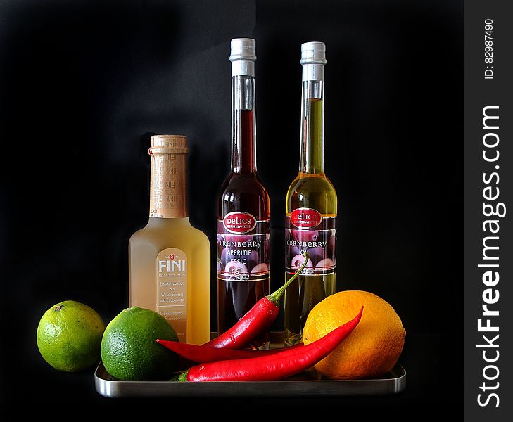 A tray with cranberry oil, white vinegar, limes and chili peppers. A tray with cranberry oil, white vinegar, limes and chili peppers.