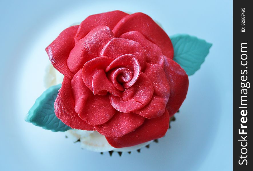 A cupcake decorated with a red fondant rose. A cupcake decorated with a red fondant rose.