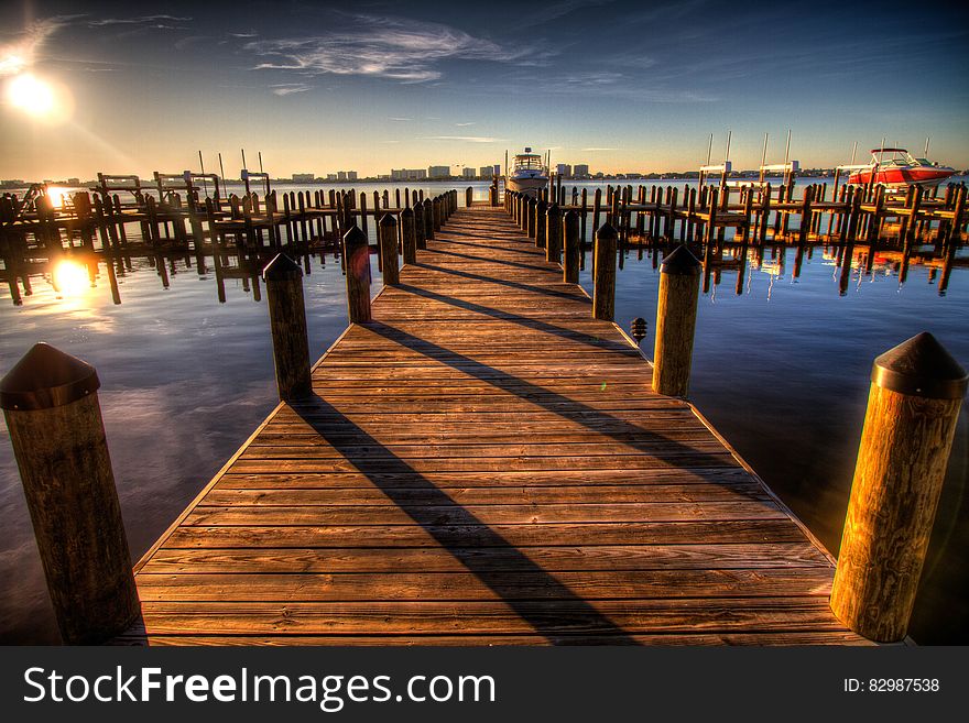 Brown Wooden Dock on Blue Water Under White Clouds and Blue Sky during Daytime