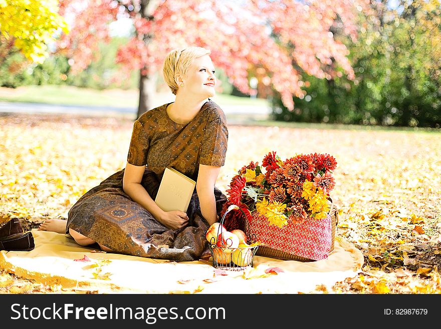 A woman with a basket of flowers in a park in the autumn. A woman with a basket of flowers in a park in the autumn.