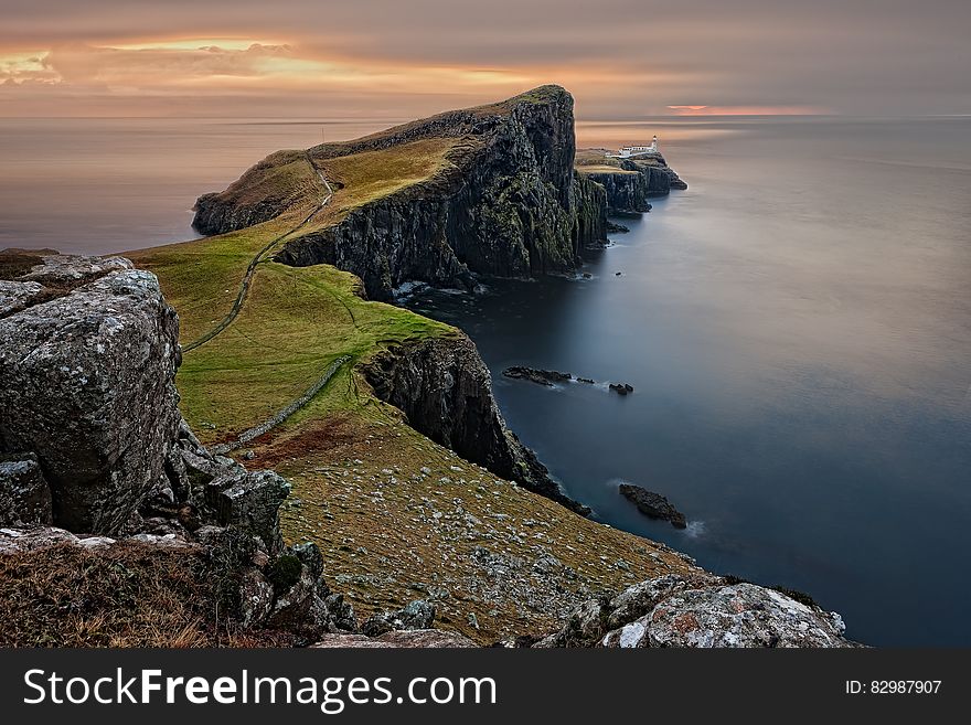 Scenic view of cliffs on the coastline of the Isle of Skye with lighthouse in the background at sunset, Scotland. Scenic view of cliffs on the coastline of the Isle of Skye with lighthouse in the background at sunset, Scotland.