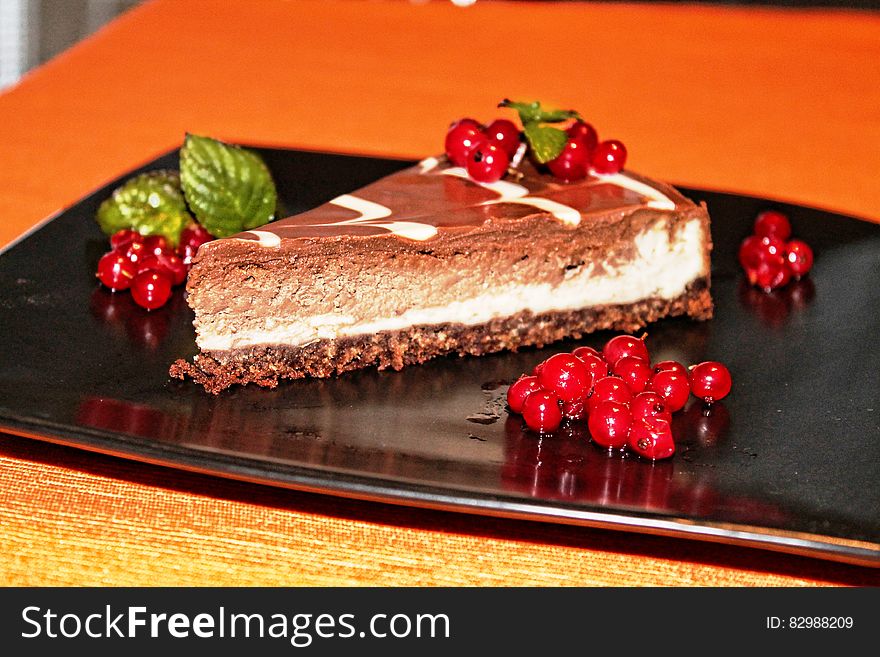 A piece of choco cheesecake with cranberry garnish.