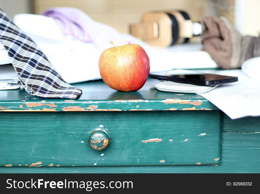 An apple on a desk with paperwork and men's clothes. An apple on a desk with paperwork and men's clothes.