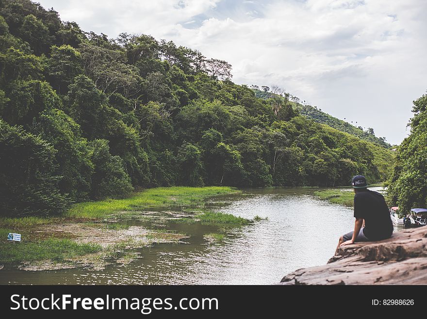 A man sitting at the rocks watching a river. A man sitting at the rocks watching a river.