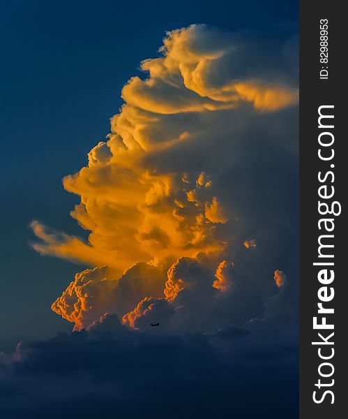 Orange sunset in white clouds of blue sky.