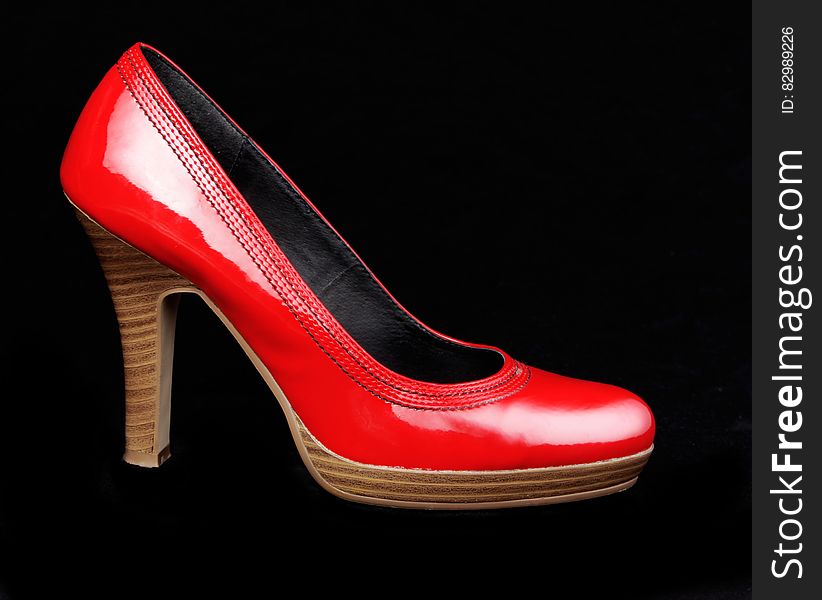 Bright red platform heel with wood sole on black background.