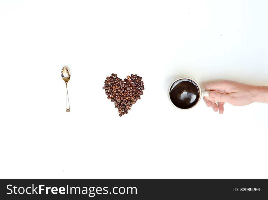 I love coffee spelled with spoon, coffee beans and hand holding coffee cup.