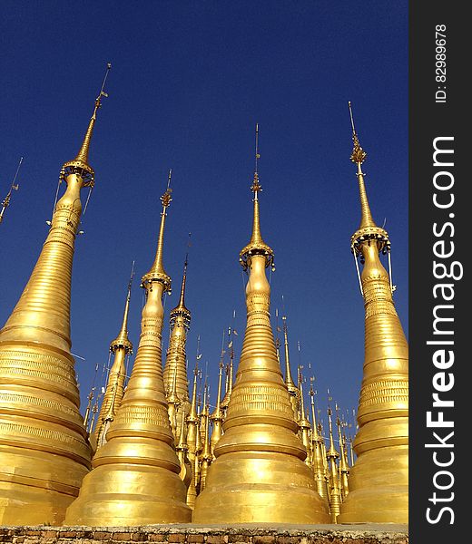 Gold Buddhist pagoda spires against blue skies in Myanmar. Gold Buddhist pagoda spires against blue skies in Myanmar.