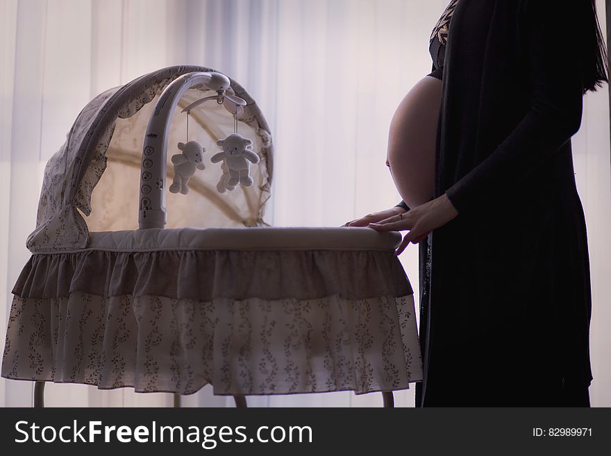 Pregnant Woman Standing Near White Brown Bassinet