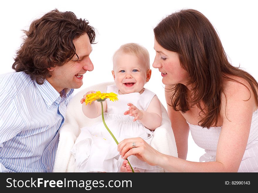 Man In White And Gray Stripe Button Up Long Sleeve Shirt Facing Baby In White Sleeveless Dress Beside Woman In White Strapless Dre