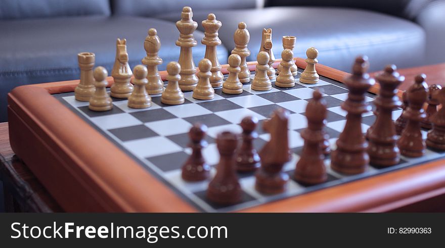 Wooden chess pieces on chessboard inside home. Wooden chess pieces on chessboard inside home.