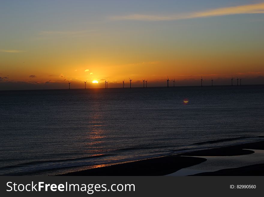 Silhouette of offshore windmills in water at sunset. Silhouette of offshore windmills in water at sunset.