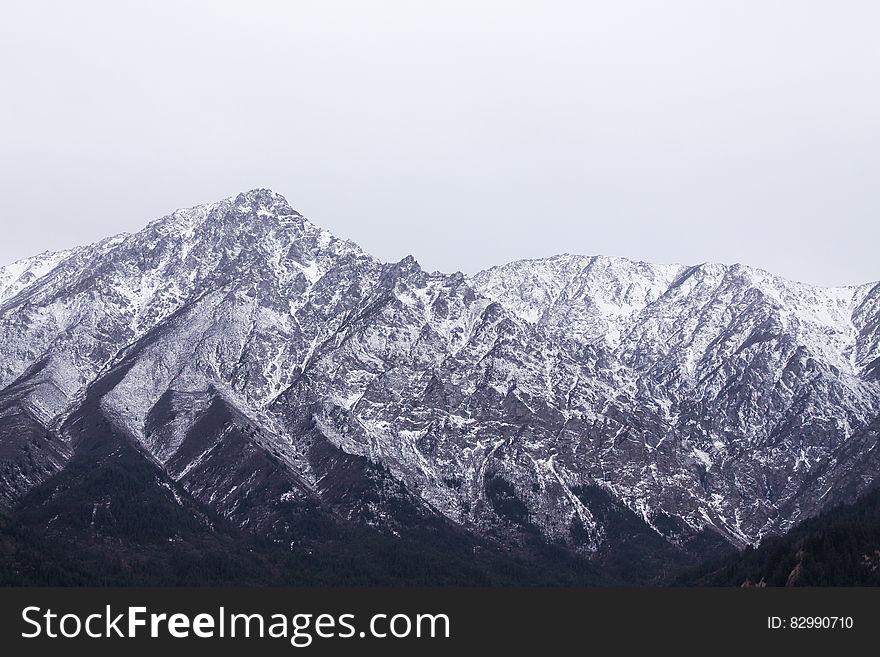 Snow covered mountain peaks against overcast skies in China. Snow covered mountain peaks against overcast skies in China.