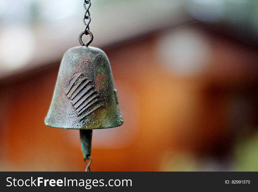 An old fashioned hanging metal bell on a blurred background. An old fashioned hanging metal bell on a blurred background.