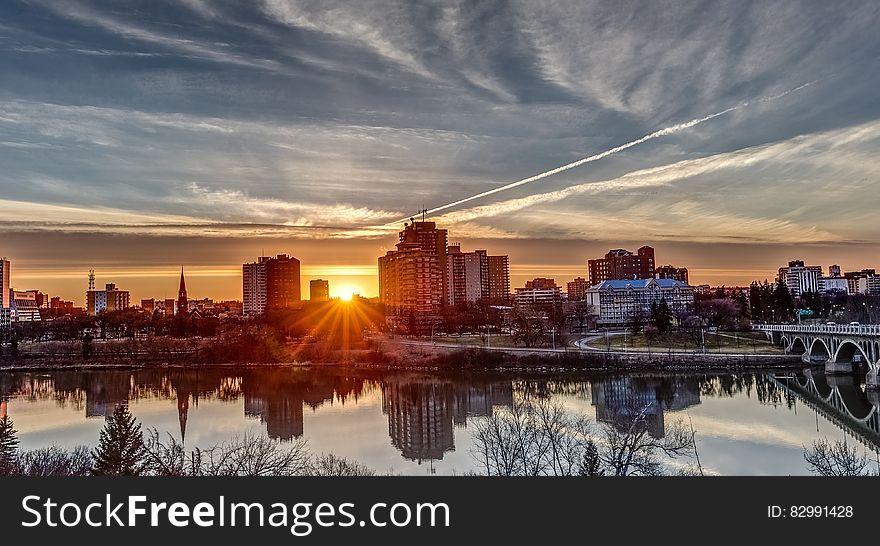 City skyline reflecting in waterfront against blue skies at sunset. City skyline reflecting in waterfront against blue skies at sunset.