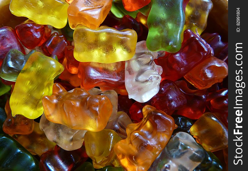 Colorful jelly baby type sweets with some identifiable as having the shape of a bear producing a colorful textured background in green, red, orange, yellow and white. Colorful jelly baby type sweets with some identifiable as having the shape of a bear producing a colorful textured background in green, red, orange, yellow and white.