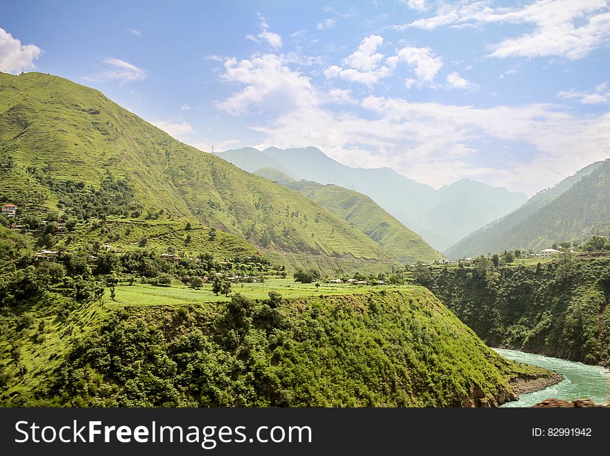 Green Valley With Wending River Under White Clouds and Blue Sky during Daytime