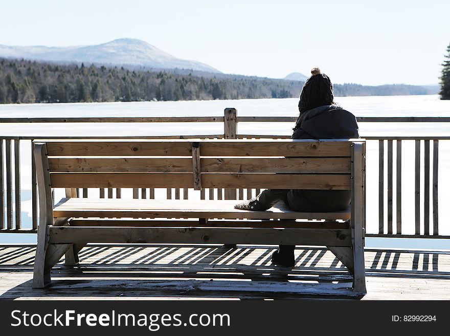 Person on Gray Jacket on Brown Wooden Bench Daytime Photo