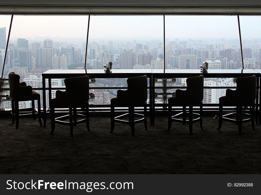 Empty conference or restaurant table and chairs against windows overlooking city skyline from modern skyscraper. Empty conference or restaurant table and chairs against windows overlooking city skyline from modern skyscraper.