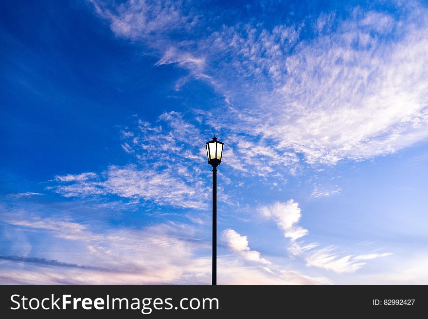 Streetlamp on post against blue skies with white clouds. Streetlamp on post against blue skies with white clouds.