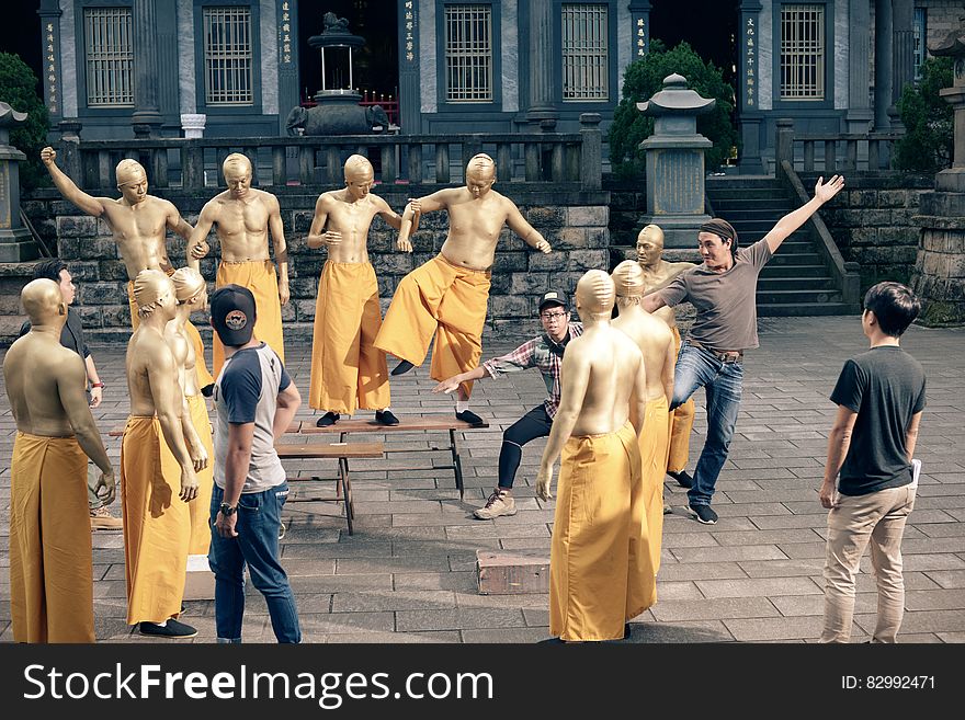 Monks practicing moves with dancers in outdoor courtyard. Monks practicing moves with dancers in outdoor courtyard.