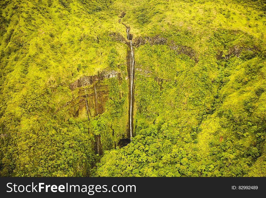 Aerial view over waterfall over green cliff. Aerial view over waterfall over green cliff.