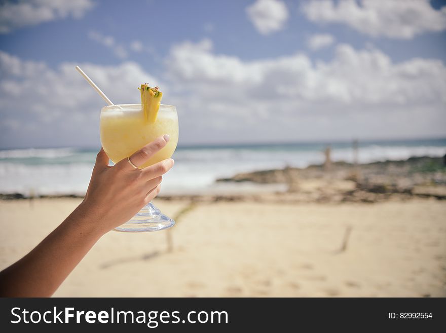 Hand holding fancy cocktail on sunny beach. Hand holding fancy cocktail on sunny beach.