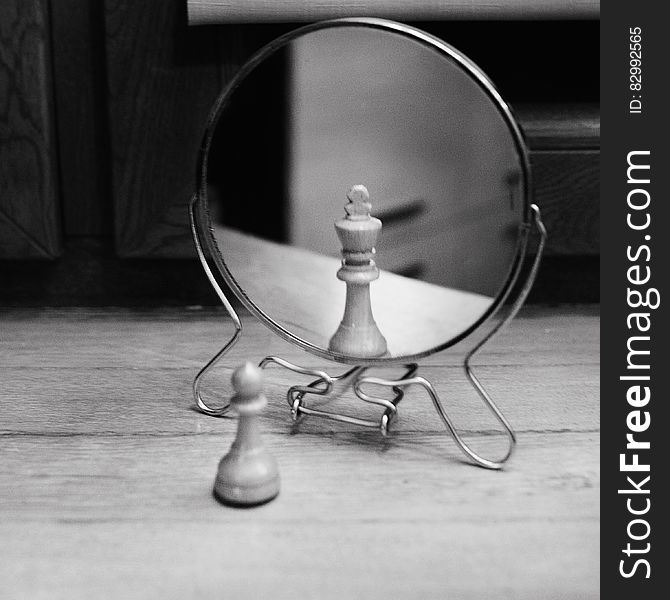 Grayscale Photo of Reversible Mirror in Front of Chess Piece