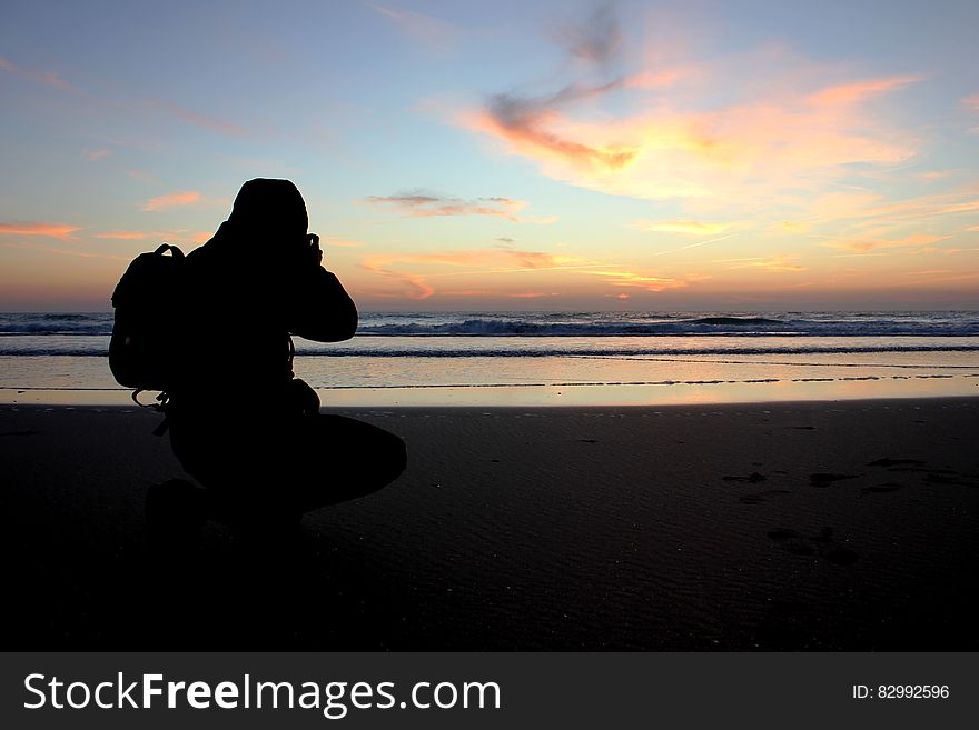 Silhouette of photographer on shoreline at sunset. Silhouette of photographer on shoreline at sunset.