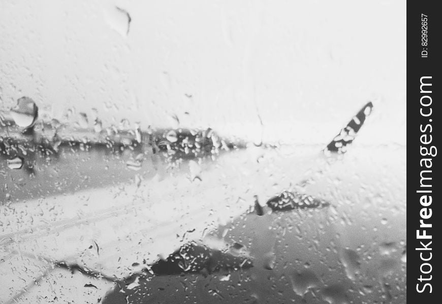 Airplane wing through rainy window in black and white.